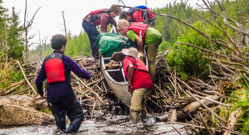 a group of students guide a canoe into the water on an outward bound course in minnesota 